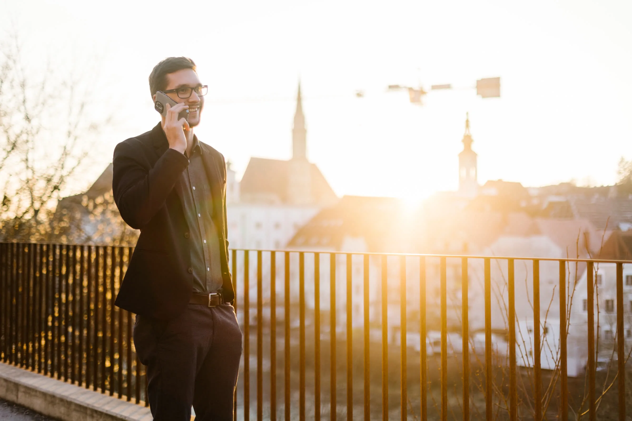 Alexander Umgeher of QMedia IT on the phone in the evening light above the old town of Steyr