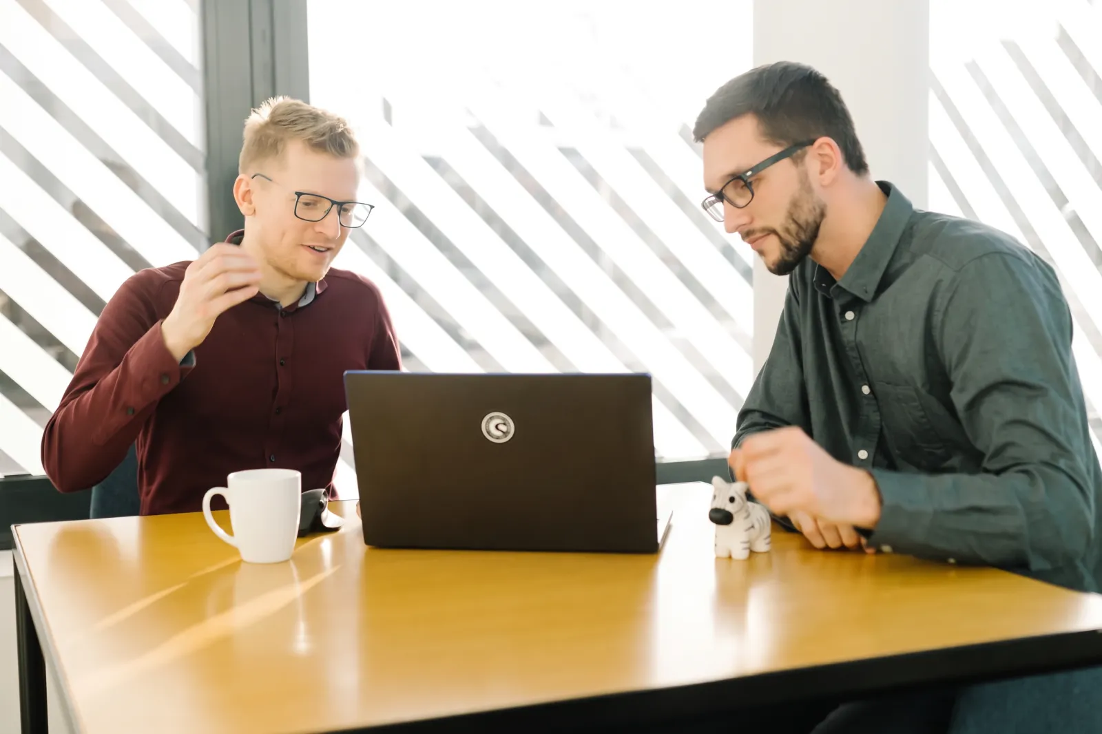 Zwei Kollegen von QMedia IT arbeiten gemeinsam am Laptop